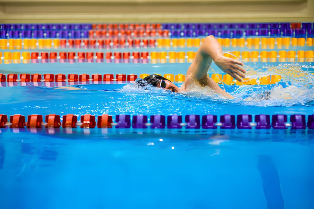 Swimmer training in a pool next to colorful lane dividers.